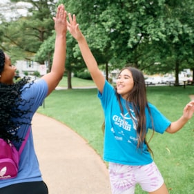  Girls on the Run participants smile while giving coach a high-five